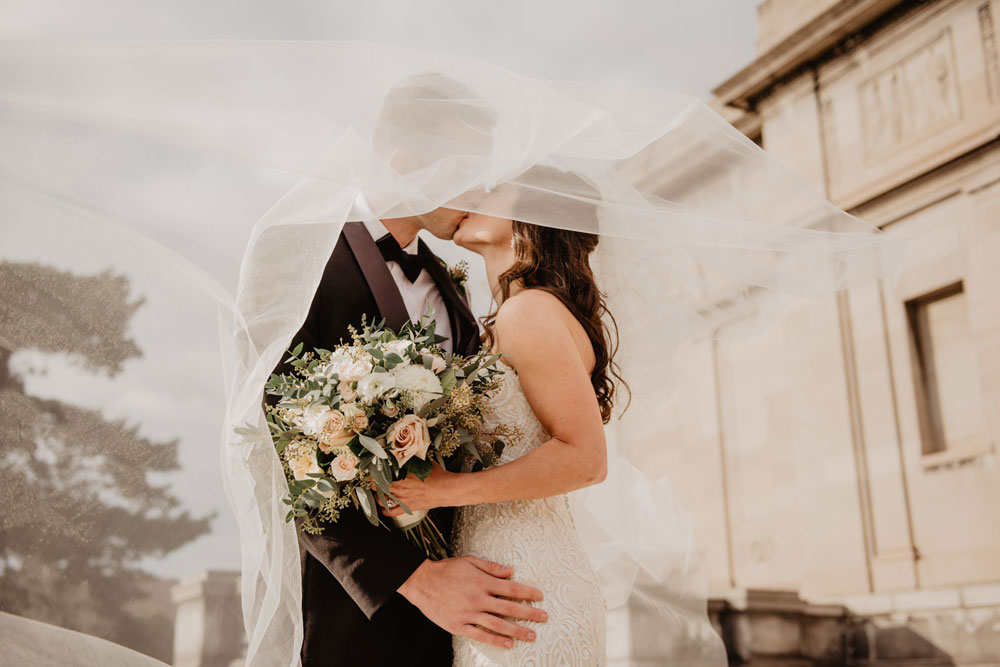 A wedding couple standing together under a veil
